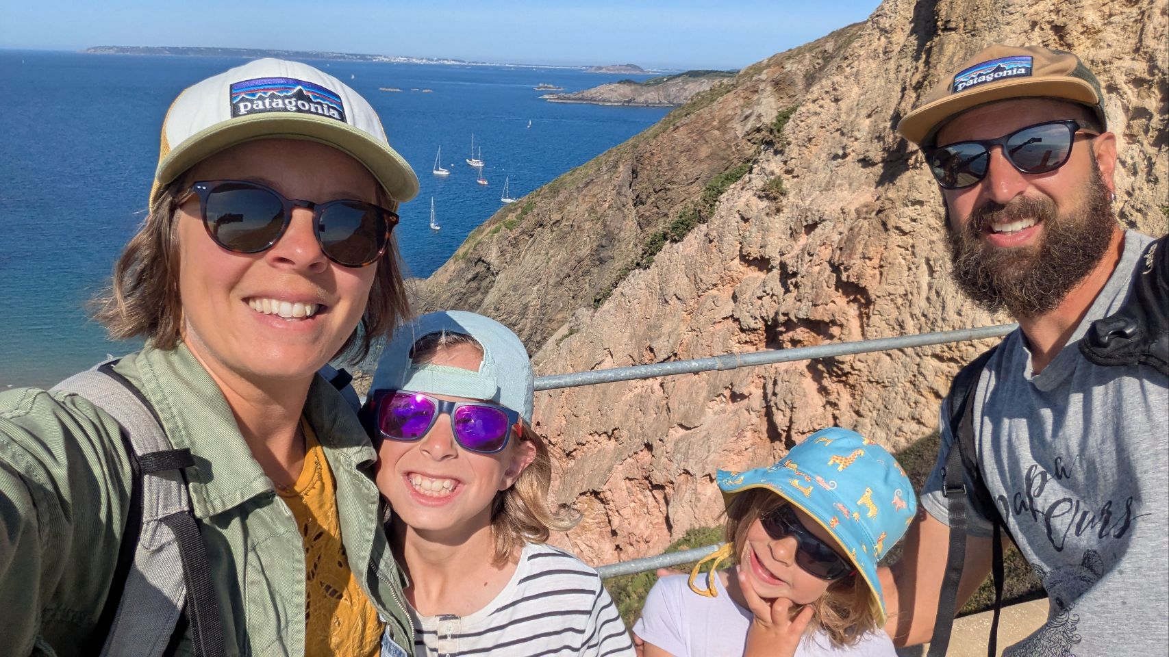 Thomas, Morgane, Gaston et Rose en randonnée sur la côte, avec des voiliers au mouillage en arrière-plan